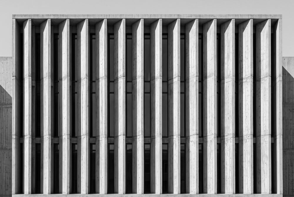 Fachada monocromática de concreto con parteluces verticales.